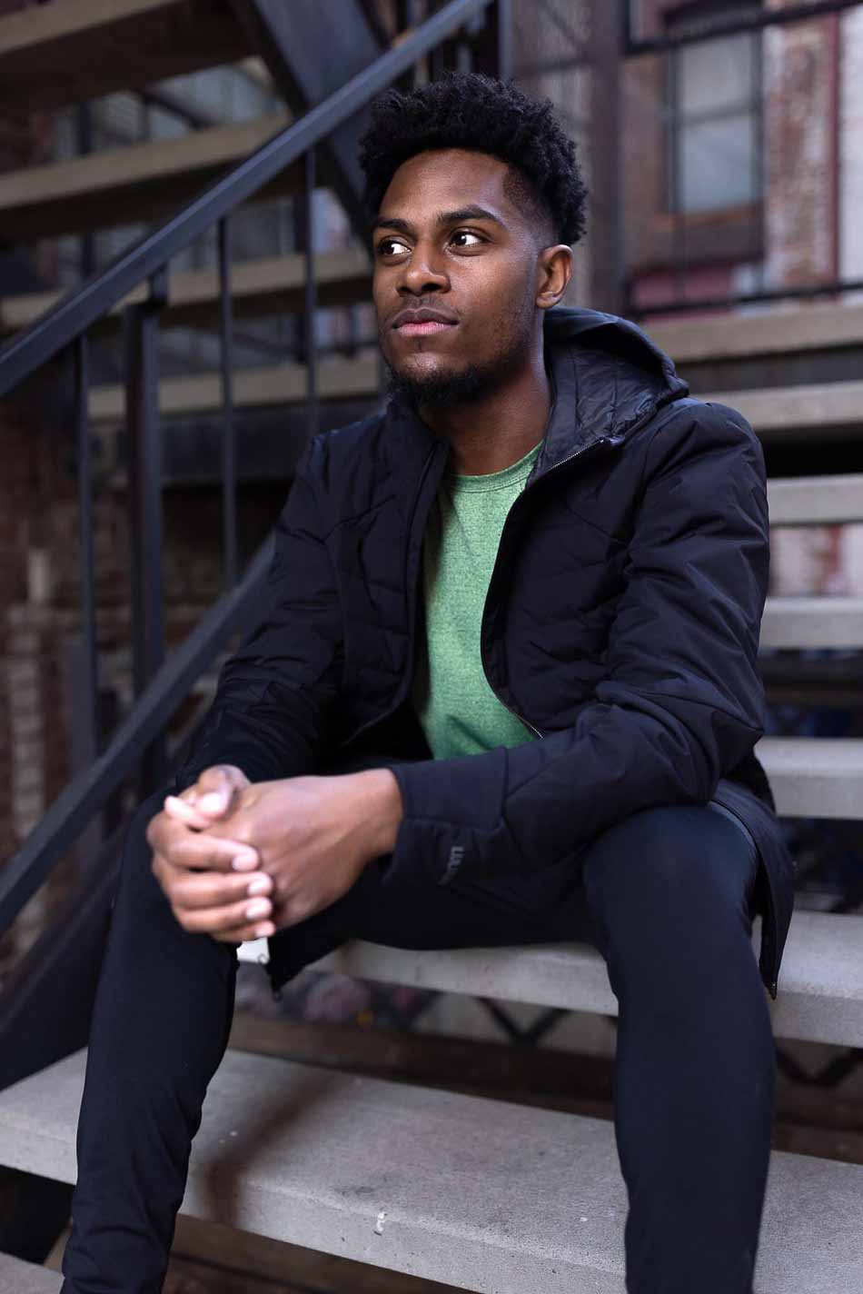 Photo of a man wearing a jacket sitting on a set of stairs